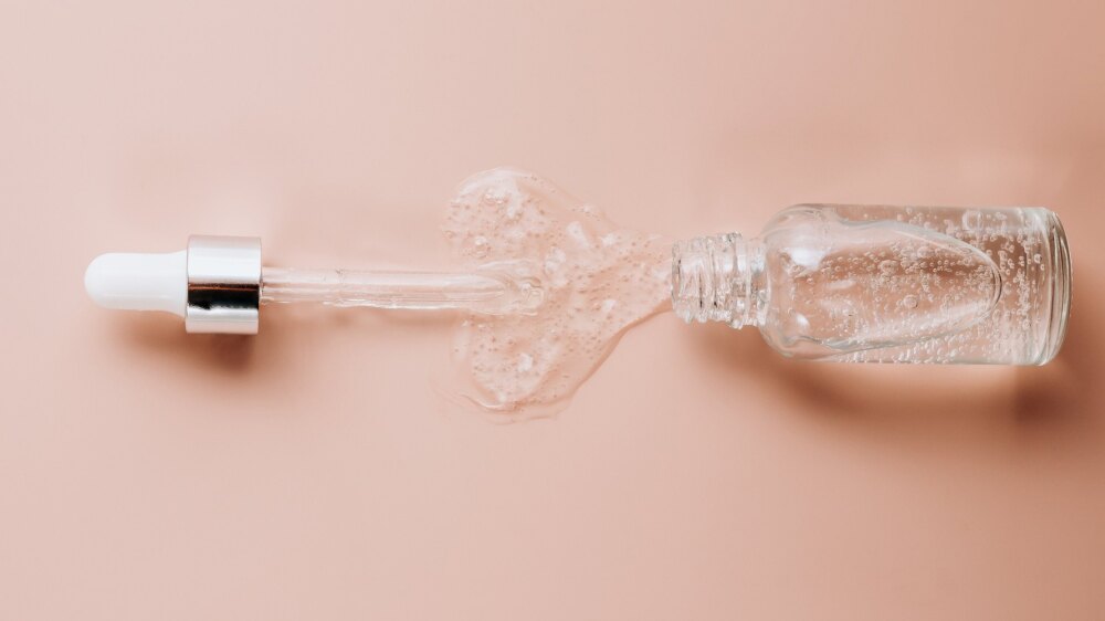 Pipette mit klarem Serum auf rosafarbenem Grund