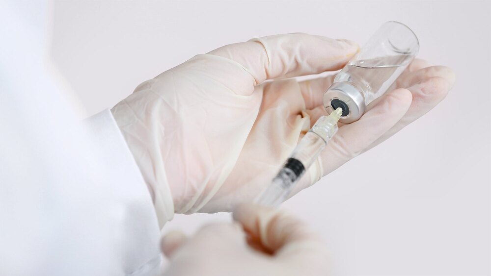 Spritze mit Filler in behandschuhter Hand